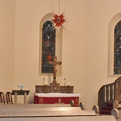 Der Chorraum der Neuwegersleber Kirche mit Altar, Kanzel und drei farbig bemalten Fenstern, auf denen Moses (von links), Jesus und Petrus abgebildet sind.