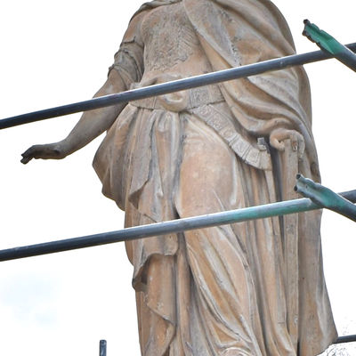 Auch wenn ein Gerüst den Blick auf die Germania etwas verdeckt, ist auf der Brust das Wappen des Deutschen Kaiserreiches genauso zu erkennen, wie ihre friedensstiftende Haltung, denn ihr rechter Arm ist nach unten gestreckt und die Hand geöffnet.