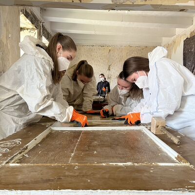 Holztüren werden von Jugendlichen der RahnSchule von Lackresten befreit, um sie anschließend denkmalgerecht zu sanieren