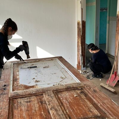 Bei den Arbeiten auf Gut 6 werden auch historische T&uuml;ren, Rahmen und weitere Bauteile sorgf&auml;ltig freigelegt und bearbeitet. Die Freiwilligen des Internationalen Bauordens unterst&uuml;tzen damit die Vorbereitung der Geb&auml;ude f&uuml;r ihre zuk&uuml;nftige Nutzung.