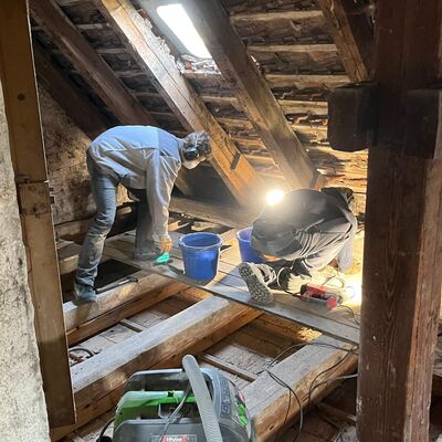 Auch im Dachgeschoss von Gut 6 wird w&auml;hrend des Arbeitseinsatzes kr&auml;ftig angepackt. Zwischen der historischen Dachkonstruktion unterst&uuml;tzen die Helfer bei Freilegungs-, Reinigungs- und vorbereitenden Arbeiten f&uuml;r die weitere Sanierung des Geb&auml;udes.